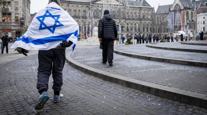 Un hombre que lleva una bandera israelí sobre sus hombros camina por la Plaza Dam en Ámsterdam, Países Bajos, el 8 de noviembre de 2024. EFE/EPA/Remko de Waal