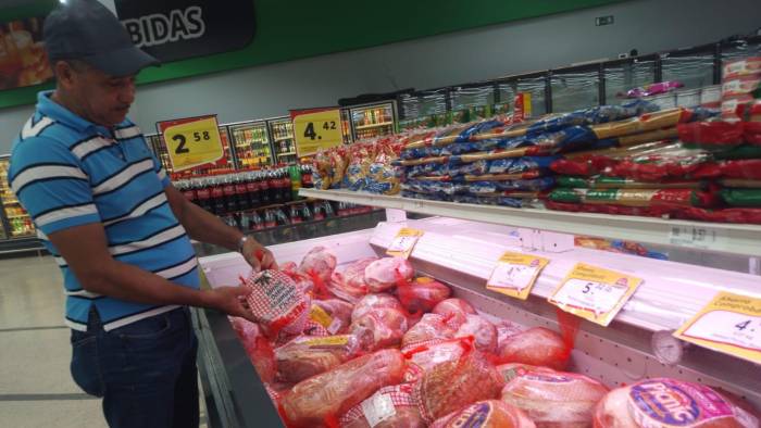 Un comprador compara los precios que tienen los jamones en uno de los supermercados de la localidad. El jamón es uno de los principales alimentos de la cena navideña de los panameños.