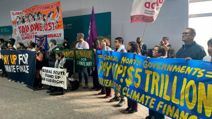 Activistas con pancartas celebran una reunión para exigir que los países ricos ayuden a las naciones.