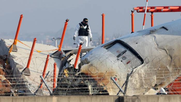 Un funcionario de un equipo de investigación científica de la Policía participa en la investigación en el lugar donde un avión se estrelló.