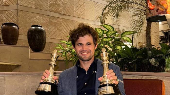 Magnus Carlsen posa con dos de sus trofeos.