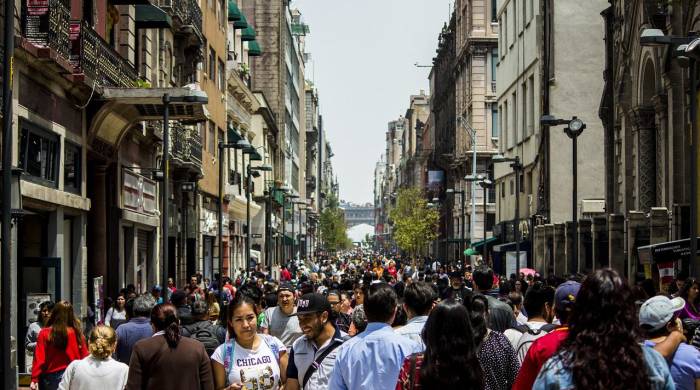 Personas caminan en una avenida de la ciudad de México, una zona de gran movimiento comercial.