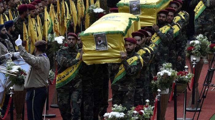 Combatientes de Hezbolá llevan los ataúdes de cuatro personas que murieron un día antes en explosiones de buscapersonas, durante una procesión fúnebre en el suburbio sur de Beirut, Líbano, el 18 de septiembre de 2024.