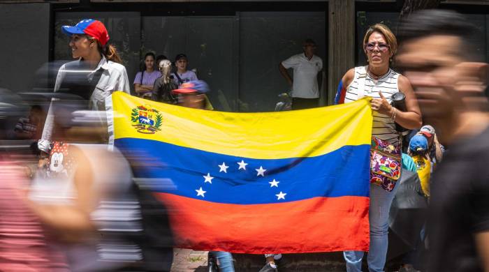 Dos mujeres sostienen una bandera de Venezuela durante una concentración convocada por la líder opositora María Corina Machado y el abanderaro de la oposición, Edmundo González Urrutia, en Caracas.