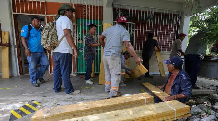 Habitantes del municipio de Felipe Carrillo Puerto refuerzan sus viviendas este jueves, en Quintana Roo.