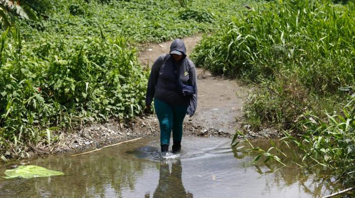 Una migrante atraviesa un riachuelo en Bajo Chiquito (Panamá), después de días de caminata para cruzar la peligrosa selva del Darién, frontera entre Colombia y Panamá.