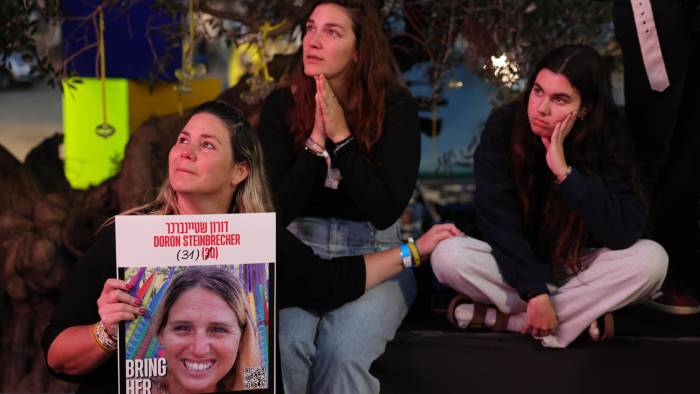 Varias personas observan una transmisión en vivo en una pantalla grande que informa sobre la liberación de tres rehenes israelíes, Romi Gonen, Emily Damari y Doron Steinbrecher, transferidos de Hamás a la Cruz Roja.