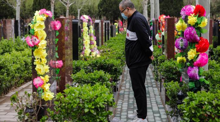 Foto de archivo de un hombre frente a una tumba en el Cementerio Waiqiao, en Pekín.