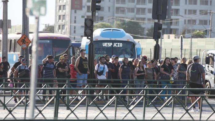 Personas esperan un bus tras un corte eléctrico que afecto a más del 90 % del país este martes, en Santiago (Chile).