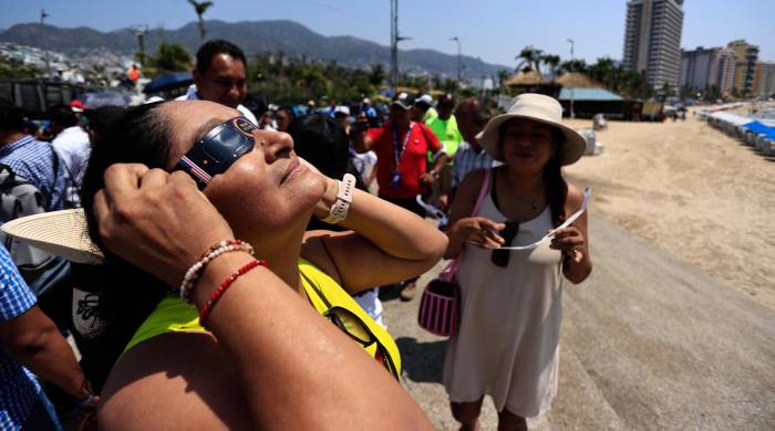 Personas observan un eclipse solar este lunes, en el balneario de Acapulco (México).