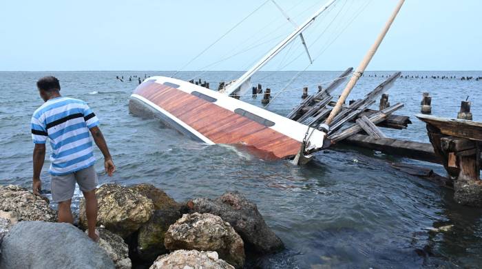 Un pescador observa a un barco hundido debido al paso del huracán Beryl este jueves, en Kingston (Jamaica).