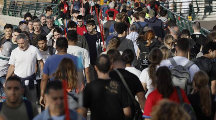 Cientos de personas cruzan la pasarela que da acceso al barrio de La Torre, en Valencia, este viernes 1 de noviembre.