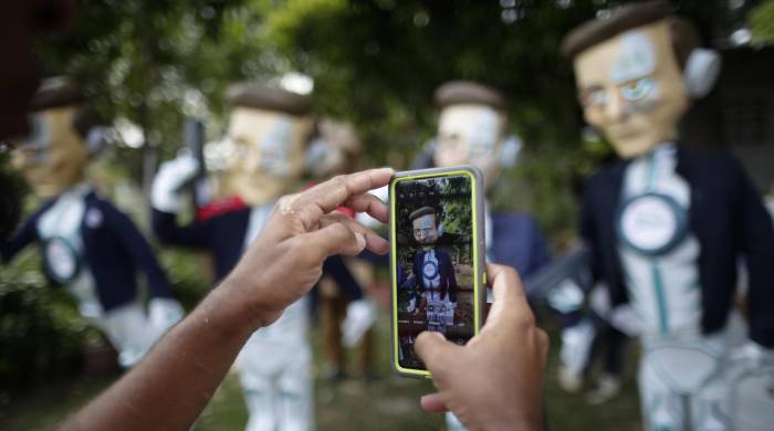 Detalle de un teléfono mientras el usuario toma fotografías a muñecos de año viejo elaborados por el artista plástico Víctor Álvarez, el 26 de diciembre de 2023, en Chame.
