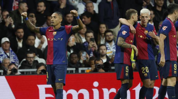 El delantero del FC Barcelona Raphinha (i) celebra tras anotar el cuarto gol de su equipo durante el partido de la jornada 11 de LaLiga EA Sports entre el Real Madrid y el FC Barcelona.