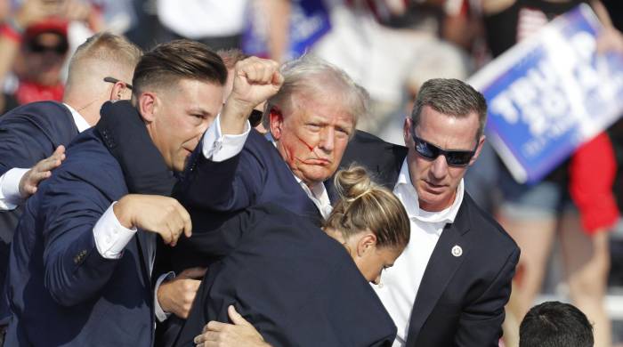 El expresidente estadounidense Donald Trump es sacado del escenario por el Servicio Secreto tras recibir un disparo en la oreja derecha.