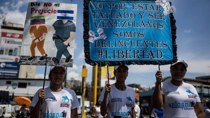 Venezolanos sostienen carteles durante la recolección de firmas en apoyo a sus compatriotas migrantes deportados desde Estados Unidos a El Salvador.