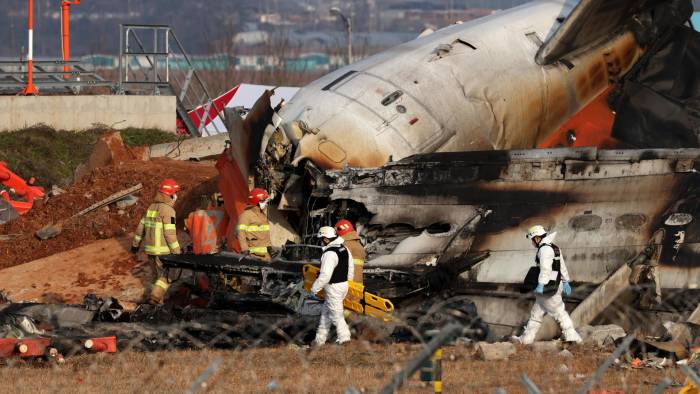 Integrantes del cuerpo del bomberos trabaja en los restos del avión de Jeju Air en el aeropuerto internacional de Muan.