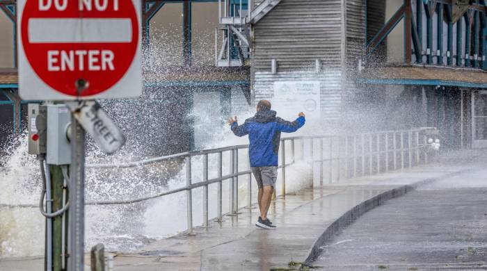 Un visitante desafía el fuerte oleaje, la marejada ciclónica y los fuertes vientos del huracán Helene.