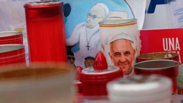 Se han colocado velas y dibujos con imágenes del papa Francisco bajo la estatua del fallecido papa Juan Pablo II frente al Hospital Agostino Gemelli, donde está hospitalizado para continuar su tratamiento por neumonía bilateral, en Roma.