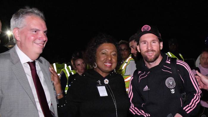 Lionel Messi (izq.) junto con la ministra de deportes de Jamaica, Olivia Babsy Grange en su arribo a Jamaica.