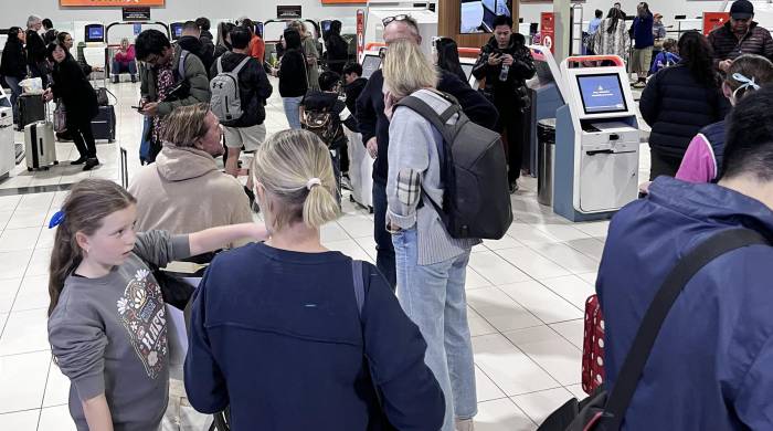 Pasajeros de al aerolínea Jetstar en el aeropuerto de Gold Coast in Bilinga (Australia) esperan frente frente a los mostradores cerrados debido al apagón global de varios sistemas informáticos.
