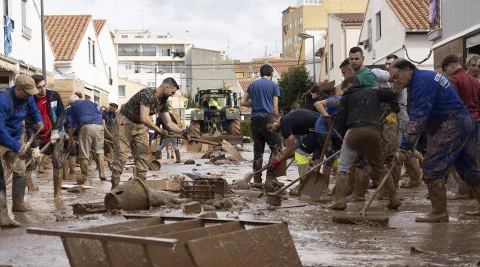 Varias personas colaboran en la limpeza de una calle afectada en la localidad de Utiel, este viernes 1 de noviembre.