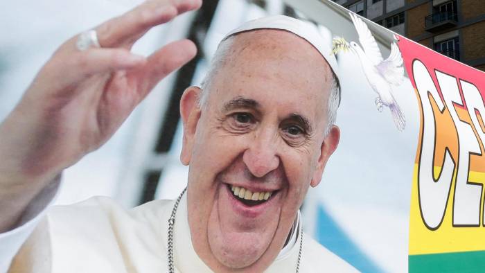 Las personas llevan una pancarta con una imagen del papa Francisco bajo la estatua del fallecido papa Juan Pablo II frente al Hospital Agostino Gemelli.